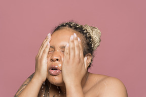 Refreshed african-american woman washing her face with both hands