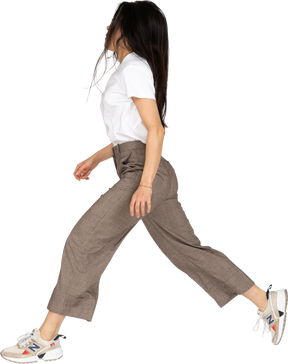 Side view of a jumping young lady in breeches and t-shirt outstretching legs
