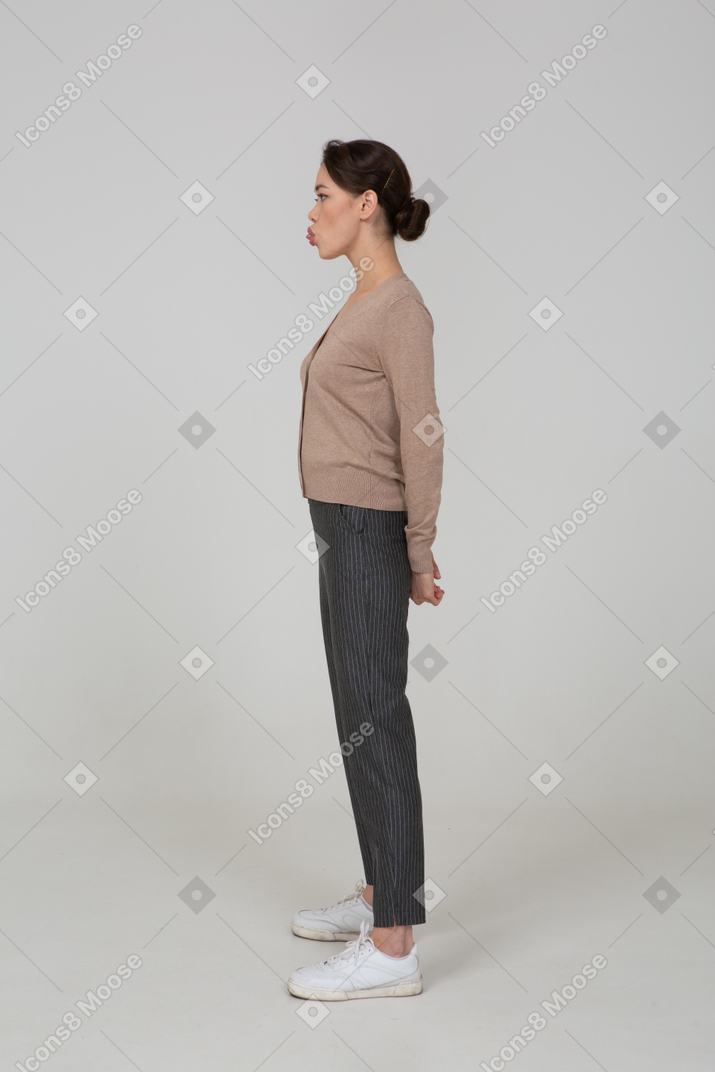 Side view of a young lady in pullover and pants showing tongue