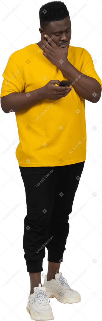 一个穿着黄色 t 恤的黑皮肤年轻男子通过电话聊天的正面视图