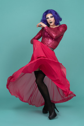Porträt einer drag queen, die in einem rosa maxirock herumwirbelt