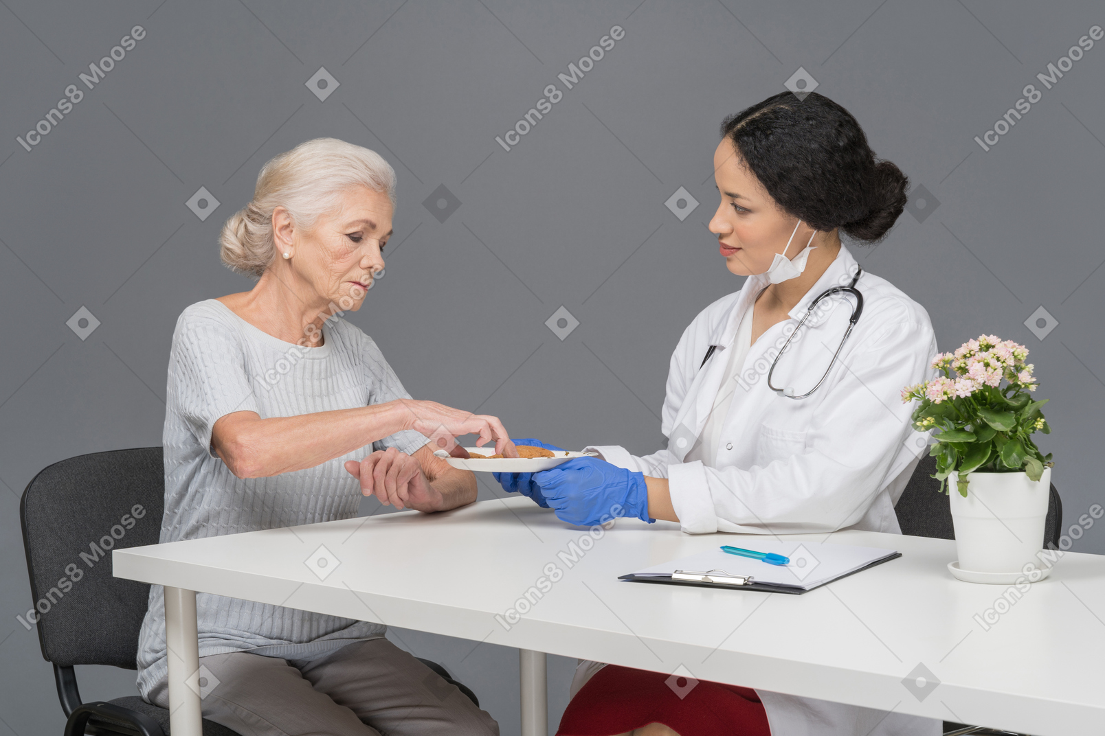 Female doctor offering her elder patient some cookies