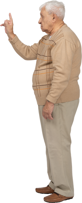 Vue latérale d'un vieil homme en vêtements décontractés pointant vers le haut avec le doigt