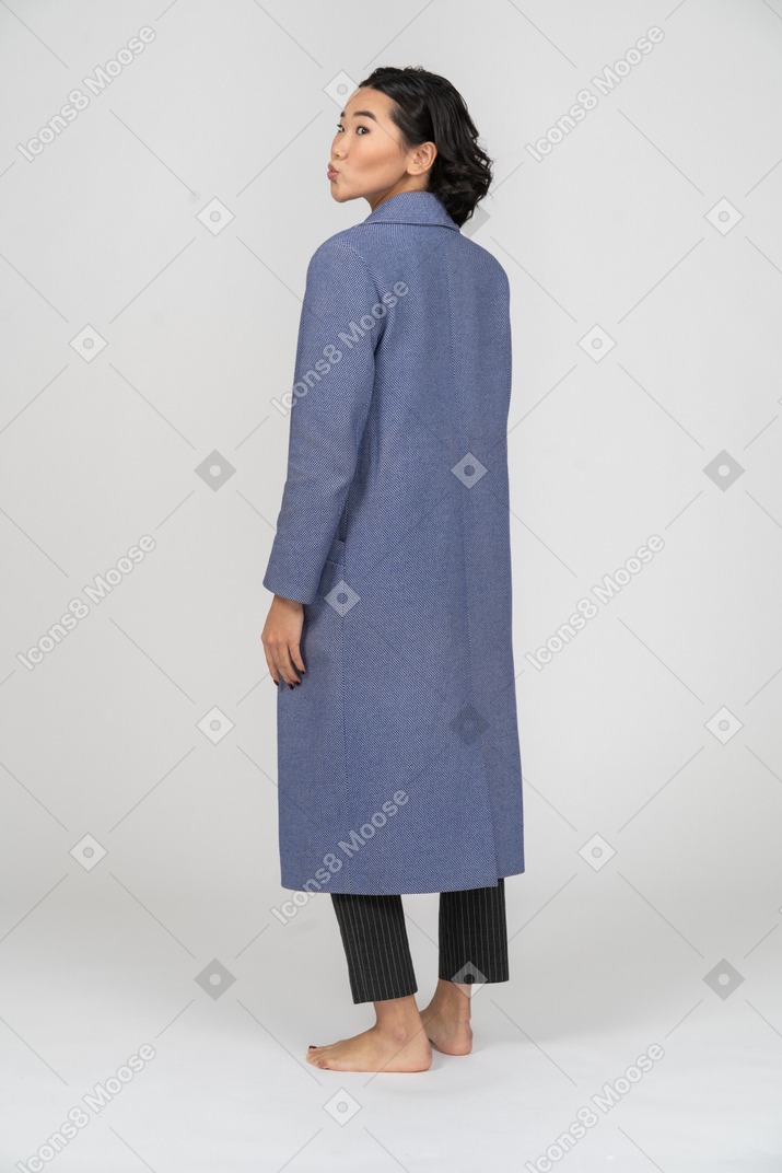Vista posteriore di una donna con le labbra increspate in cappotto