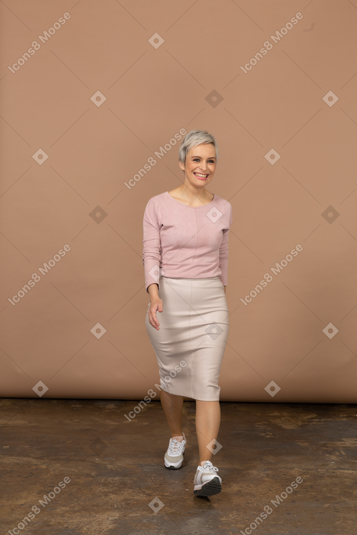 Front view of a happy woman in casual clothes walking forward