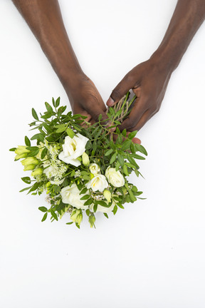 Mãos masculinas pretas segurando o buquê de flores