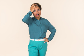 Black woman with a short haircut, wearing all blue, standing against a plain pastel background, looking emotional