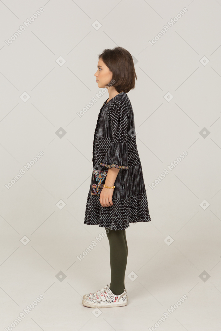 Vista laterale di una bambina perplessa in abito che lavora a maglia le sopracciglia