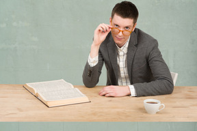 A man sitting at a table with a book and a cup of coffee