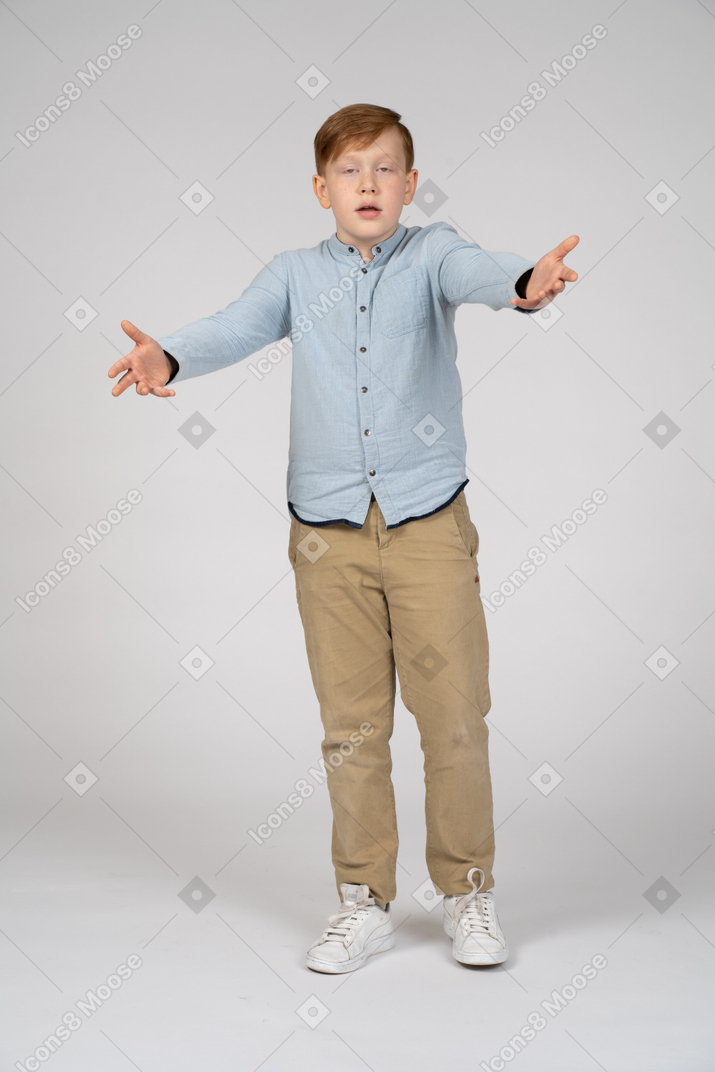 一个男孩站着伸出双臂，看着相机的正面图