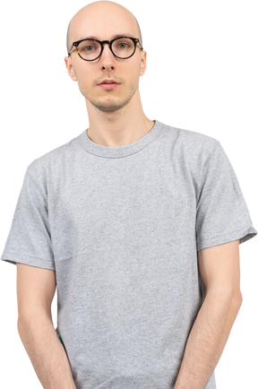 Homme chauve en t-shirt gris regardant la caméra