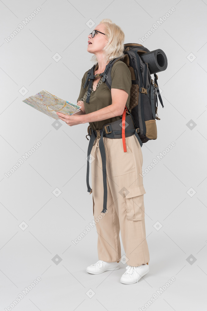 Female mature tourist carrying backpack and holding travel map