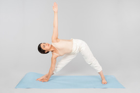 Joven mujer india de pie sobre la estera de yoga en una pose