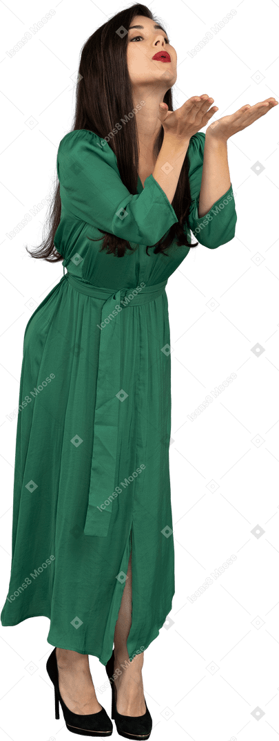 공기 키스를 보내는 녹색 드레스를 입은 젊은 아가씨의 3/4보기