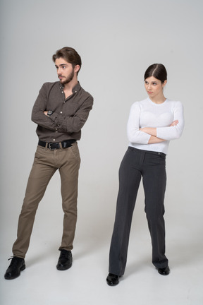 Трехчетвертный вид молодой пары в офисной одежде, скрещивающей руки