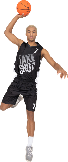 Vista frontal de um jovem jogador de basquete marcando um ponto