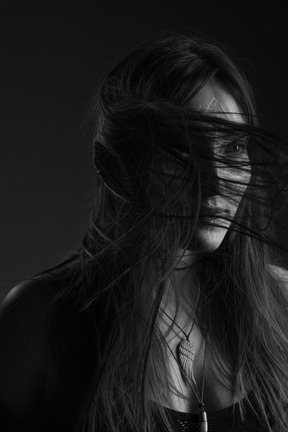 Noir three-quarter portrait of a young female with ethnic facial art and messy hair