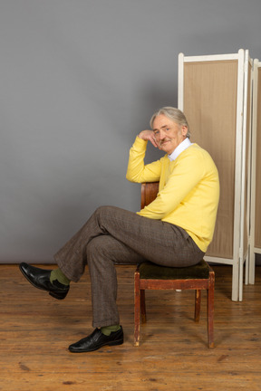 Side view of man sitting on chair and looking at camera