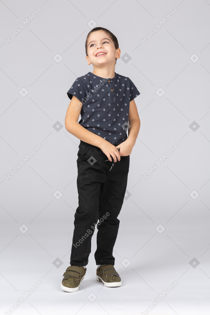 Front view of a happy boy in casual clothes looking up