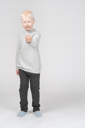 Niño con los ojos cerrados extendiendo la mano vacía