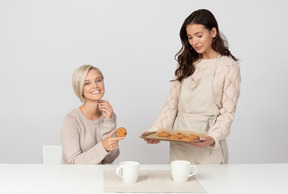 友人に自家製クッキーを提供する若い女性