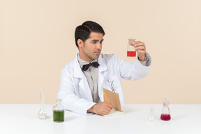 Male scientist holding bulb and sitting at the table