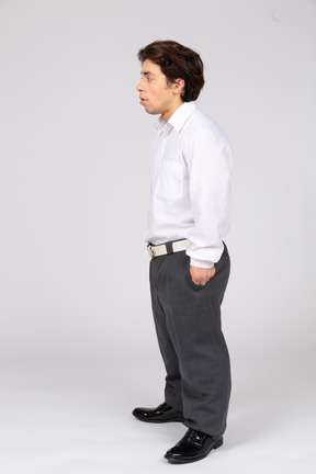 Vista lateral de um trabalhador de escritório masculino em pé com as mãos nos bolsos
