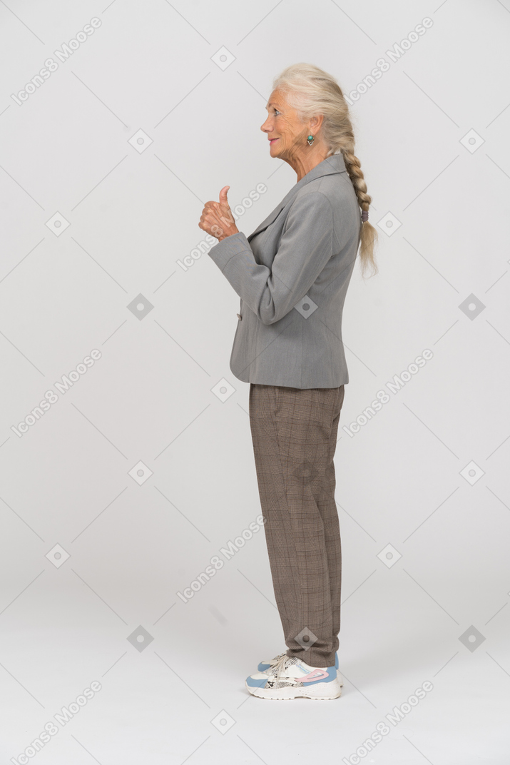 Side view of a happy old lady in suit showing thumb up