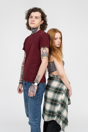 Teenage girl and boy standing back to back