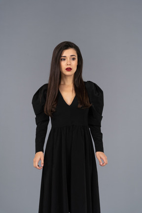 一位年轻的女士，穿着黑裙子站着不动的前视图