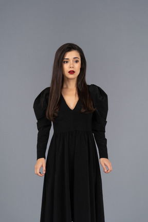 Front view of a young lady in a black dress standing still