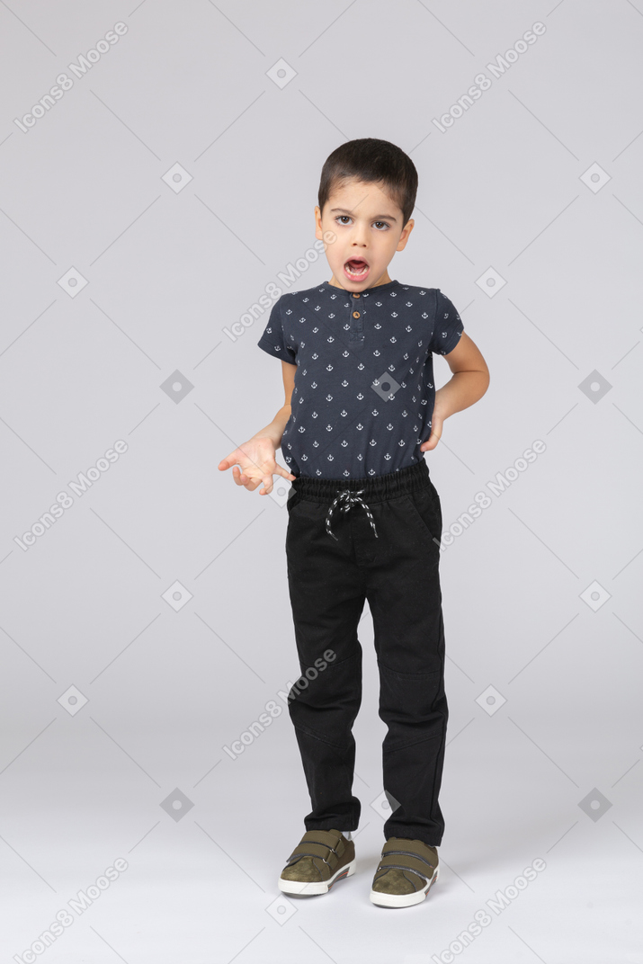 Front view of an emotional boy standing with hand on back and arguing