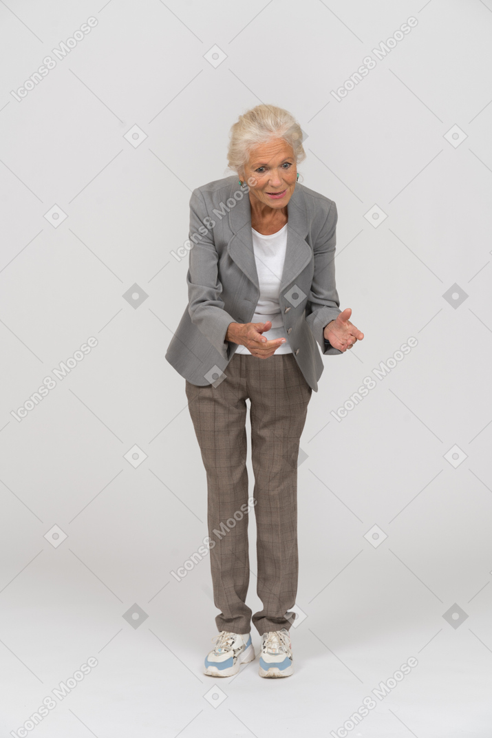 Front view of an old lady in suit bending down and explaining something