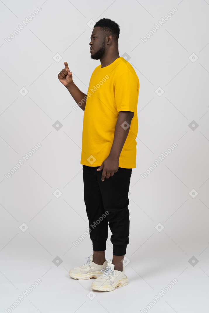 Dreiviertelansicht eines jungen dunkelhäutigen mannes in gelbem t-shirt, das die größe von etwas zeigt