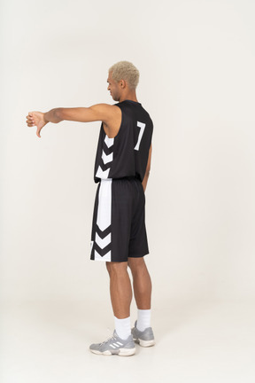 Dreiviertel-rückansicht eines jungen männlichen basketballspielers, der den daumen nach unten zeigt