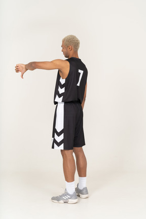 Three-quarter back view of a young male basketball player showing thumb down