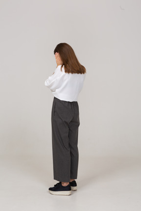 Vista posteriore di tre quarti di una giovane donna in abiti da ufficio che tocca le orecchie
