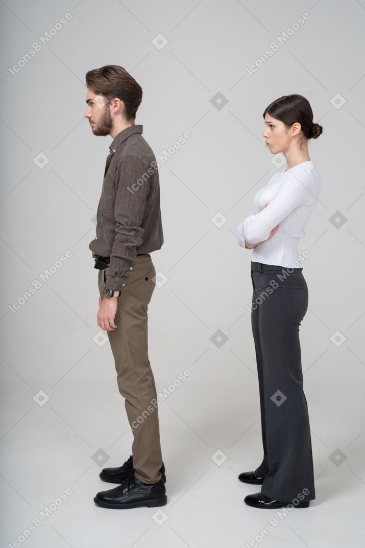 一对不高兴的年轻夫妇，在办公室服装中的侧视图