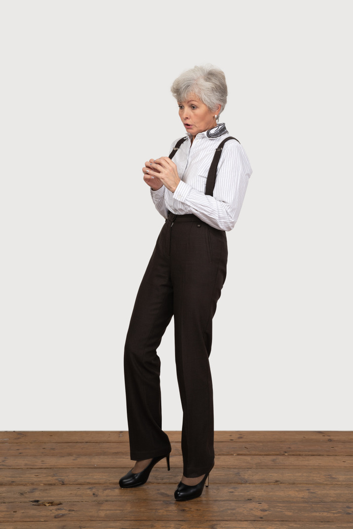 Three-quarter view of a scared old lady in office clothing holding hands together