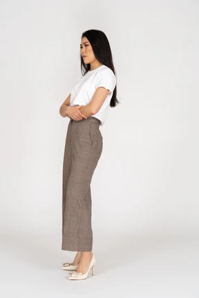 Three-quarter view of a displeased young lady in breeches and t-shirt crossing hands