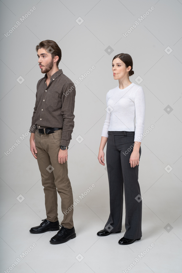 Vista de tres cuartos de una pareja joven en ropa de oficina metiendo las mejillas
