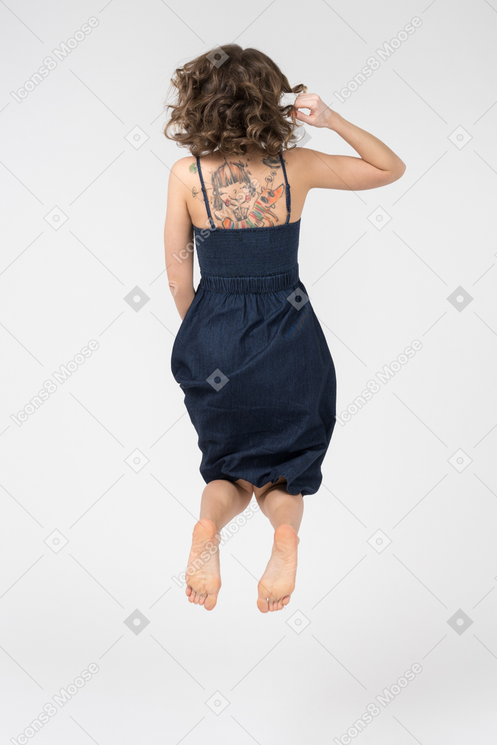 Unrecognizable tattooed girl jumping up high back to camera
