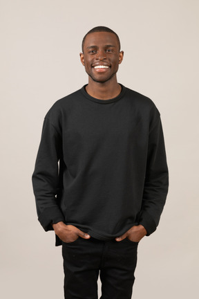 Front view of a smiling young man keeping hands in pockets