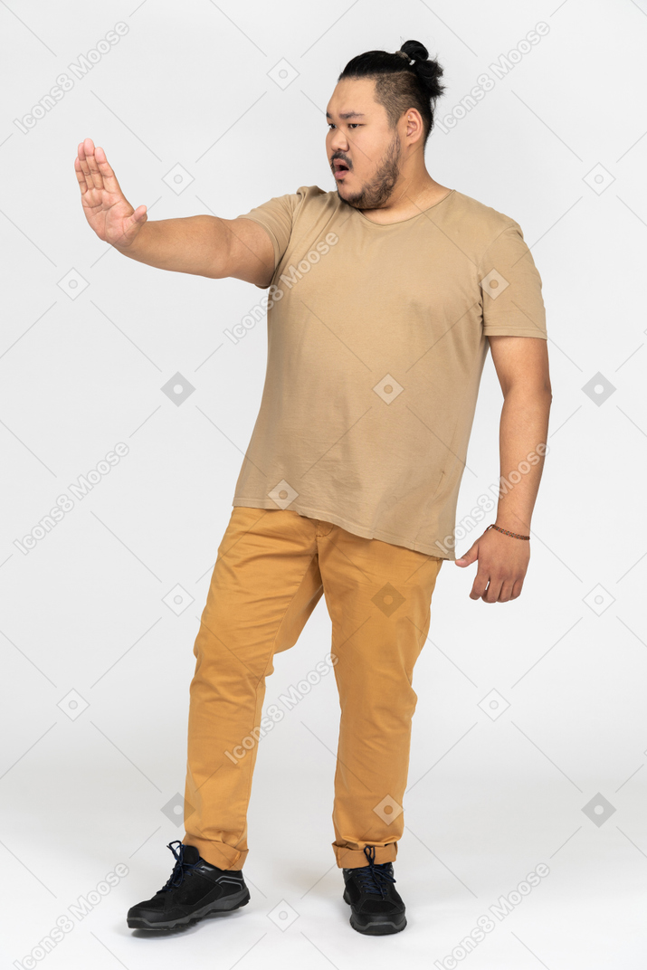 Serious asian man standing with outstretched hand making a stop gesture