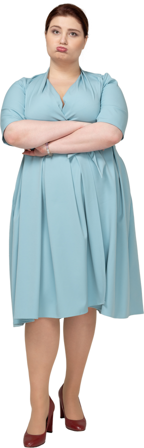 Вид спереди женщины в синем платье, стоящей со скрещенными руками