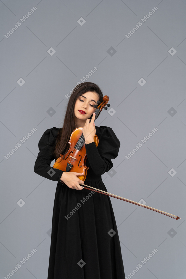 Gros plan d'une jeune femme en robe noire embrassant son violon