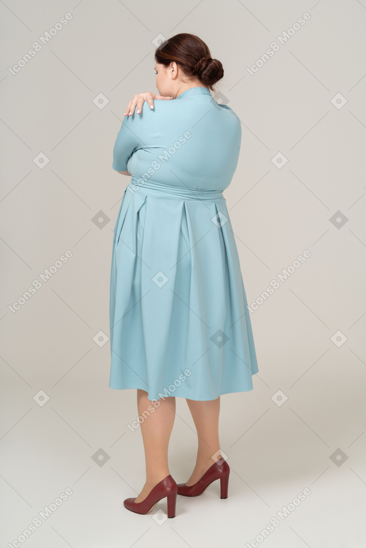 一个穿着蓝色连衣裙的女人拥抱自己的后视图