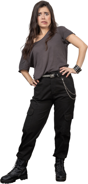 Front view of a surprised grimacing female rocker putting hands on hips
