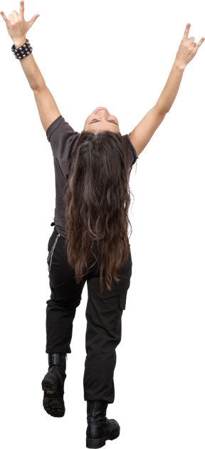 Vista posterior de una mujer joven inclinándose hacia atrás y mostrando gesto de rock