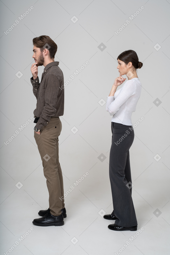 一对周到的年轻夫妇，在办公室的衣服，抚摸下巴的侧视图